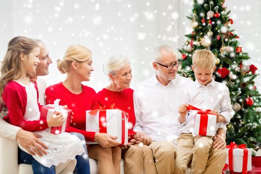 family, holidays, generation, christmas and people concept - smiling family with gift boxes sitting on couch at home