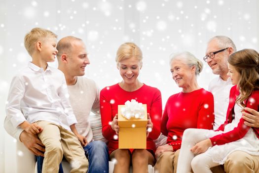 family, holidays, generation, christmas and people concept - smiling family with gift box sitting on couch at home