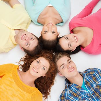 friendship, youth and people - group of smiling teenagers lying on floor in circle