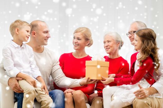 family, holidays, generation, christmas and people concept - smiling family with gift box sitting on couch at home