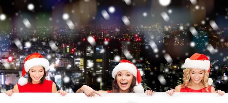 christmas, x-mas, people, advertisement and sale concept - happy women in santa helper hat with blank white board over snowy city background