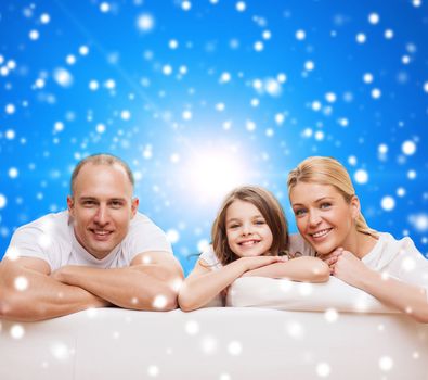 family, childhood, christmas holidays and people - smiling mother, father and little girl over blue snowy background