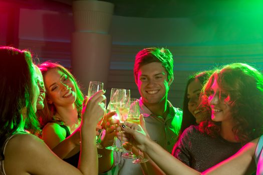 party, holidays, celebration, nightlife and people concept - smiling friends with glasses of champagne in club