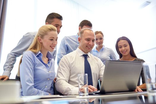 business, people, technology and communication concept - smiling business team with laptop computer making video conference in office