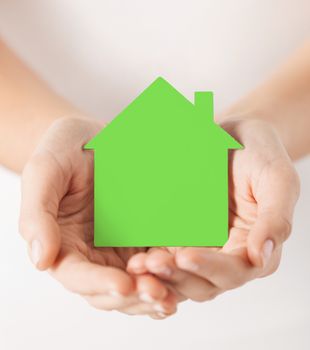 real estate and family home concept - closeup picture of female hands holding green blank paper house