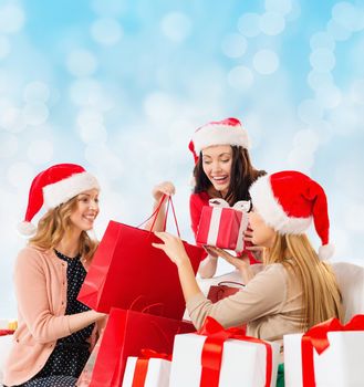 sale, winter holidays, christmas and people concept - smiling young woman in santa helper hat with gifts and shopping bags over blue lights background