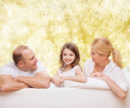 family, childhood, holidays and people - smiling mother, father and little girl over yellow lights background