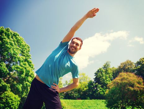 fitness, sport, training and lifestyle concept - smiling man stretching hand outdoors