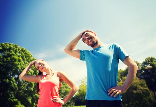 fitness, sport, training and lifestyle concept - smiling couple stretching outdoors