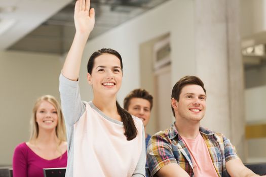 education, high school, teamwork and people concept - group of smiling students raising hand in lecture hall