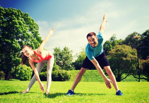 fitness, sport, training and lifestyle concept - smiling couple stretching outdoors