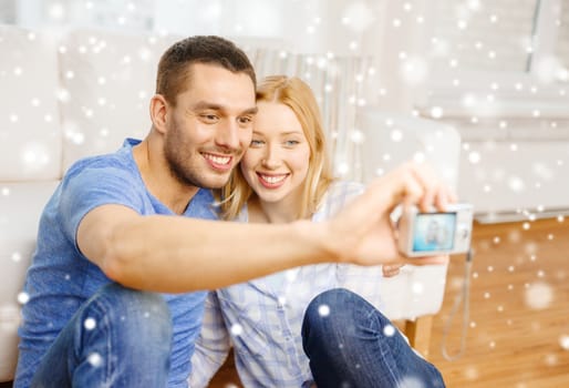 love, family, technology and people concept - smiling couple taking selfie with digital camera at home