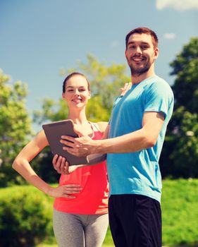 fitness, sport, friendship, technology and lifestyle concept - smiling couple with tablet pc computer outdoors