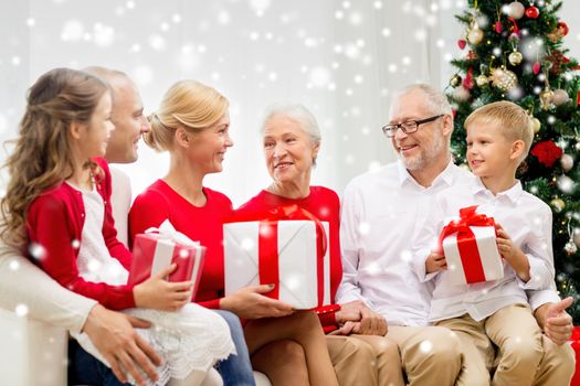 family, holidays, generation, christmas and people concept - smiling family with gift boxes sitting on couch at home