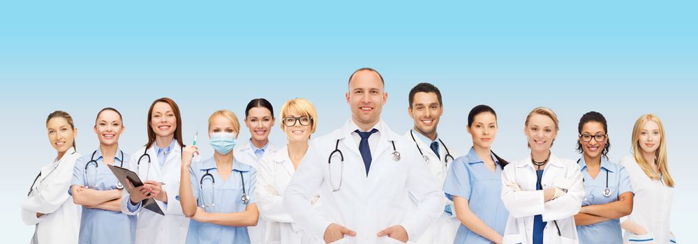 medicine, profession, teamwork and healthcare concept - international group of smiling medics or doctors with clipboard and stethoscopes over blue background