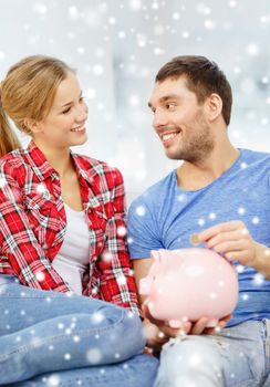 money, home, finance and relationships concept - smiling couple with piggybank sitting on sofa