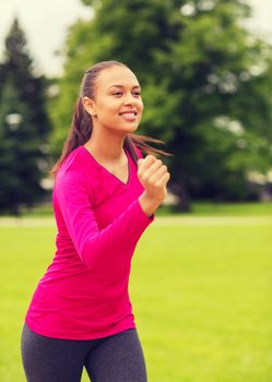 sport, fitness, health and people concept - smiling young african american woman running outdoors