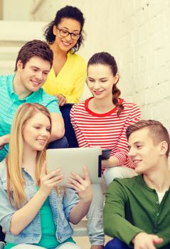 education and technology concept - smiling students with tablet pc computer sitting on staircase