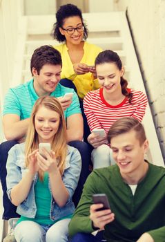 education, school and technology concept - smiling students with smartphone texting at school