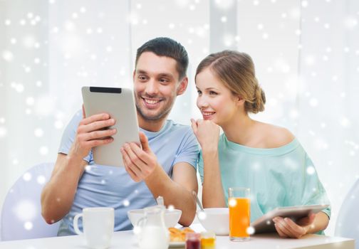 food, family, people and technology concept - smiling couple with tablet pc computers reading news and having breakfast at home