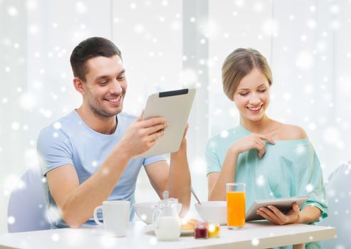 food, family, people and technology concept - smiling couple with tablet pc computers reading news and having breakfast at home