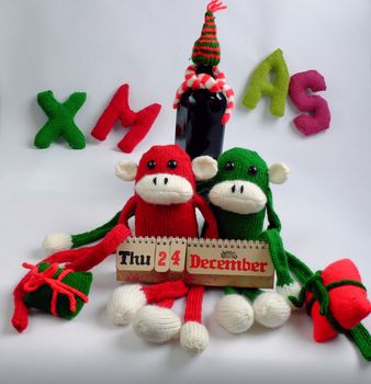 Funny Christmas background, two knitted monkey hold noel wine bottle, Xmas alphabet in red and green yarn, symbol to merry christmas and happy new year, a year of monkeys