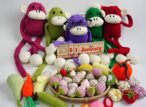 Family of stuffed animal sit at new year party, group of knitted monkey in colorful yarn, symbol of 2016, funny homemade toy on white background, handmade food and calendar to happy new year