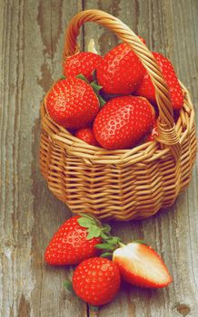 Fresh Ripe Strawberries in Wicker Basket closeup on Rustic Wooden background. Retro Styled