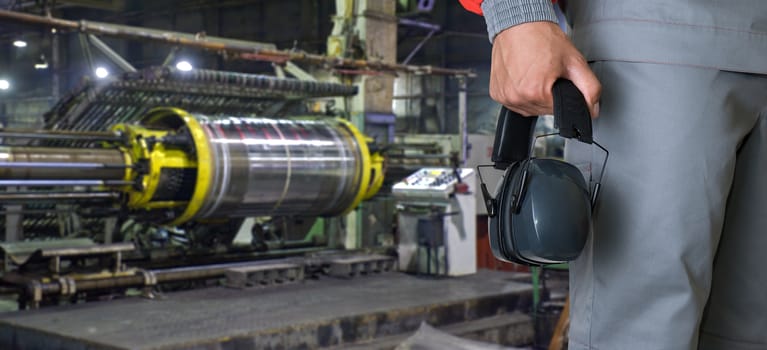 Worker with protective headphone at man hands at industrial factory