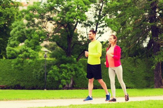 fitness, sport, friendship and lifestyle concept - smiling couple running outdoors