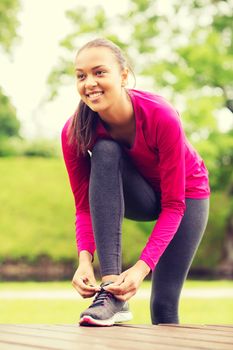 sport, exercise, park and lifestyle concept - smiling african american woman exercising outdoors