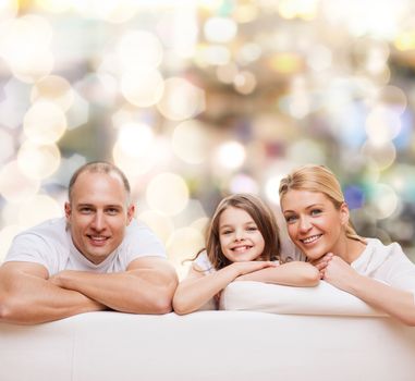 family, childhood, holidays and people - smiling mother, father and little girl over lights background