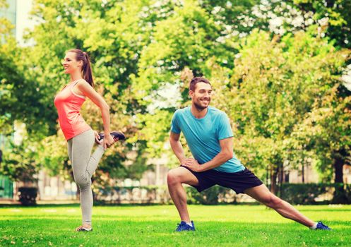 fitness, sport, training and lifestyle concept - smiling couple stretching outdoors