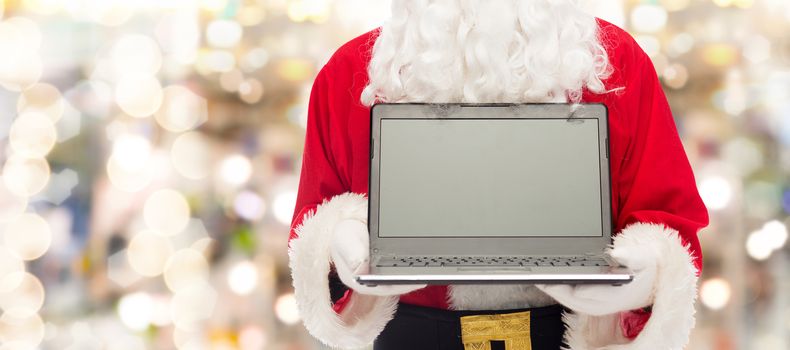 christmas, advertisement, technology, and people concept - close up of santa claus with laptop computer over lights background