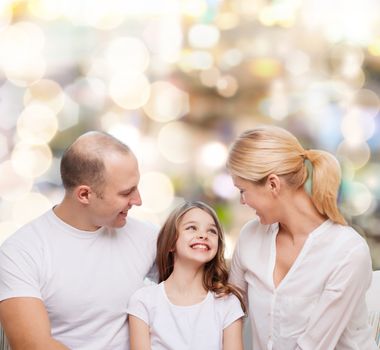 family, childhood, holidays and people - smiling mother, father and little girl over lights background