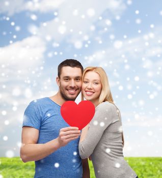 love, people and family concept - smiling couple with red paper heart shape hugging over blue sky, snow and grass background