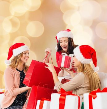 sale, winter holidays, christmas and people concept - smiling young woman in santa helper hat with gifts and shopping bags over beige lights background