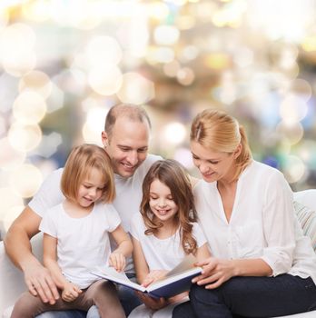 family, childhood, holidays and people - smiling mother, father and little girls reading book over lights background