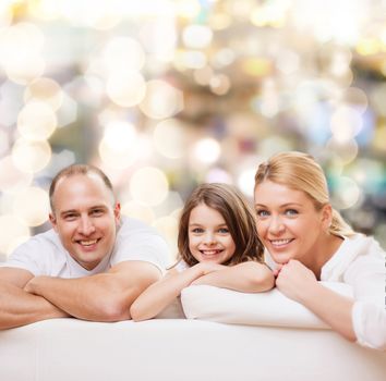 family, childhood, holidays and people - smiling mother, father and little girl over lights background