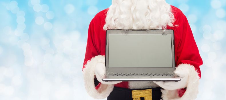 christmas, advertisement, technology, and people concept - close up of santa claus with laptop computer over blue lights background