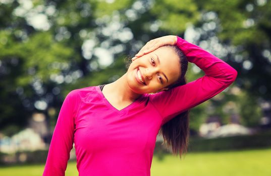 fitness, sport, training, park and lifestyle concept - smiling woman stretching leg outdoors