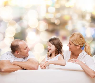 family, childhood, holidays and people - smiling mother, father and little girl over lights background