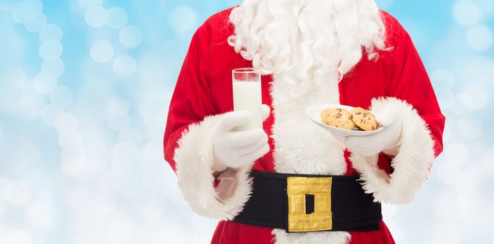 christmas, holidays, food, drink and people concept -close up of santa claus with glass of milk and cookies over blue lights background