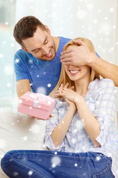 love, holiday, celebration and family concept - smiling man surprises his girlfriend with present at home