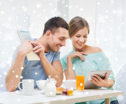 food, family, people and technology concept - smiling couple with tablet pc computers reading news and having breakfast at home