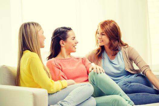 friendship and happiness concept - three girlfriends having a talk at home