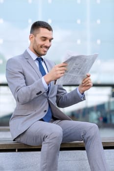 business, hot drinks and people and concept - young smiling businessman with newspaper over office building