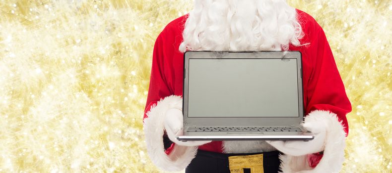 christmas, advertisement, technology, and people concept - close up of santa claus with laptop computer over yellow lights background