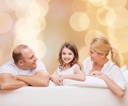 family, childhood, holidays and people - smiling mother, father and little girl over beige lights background