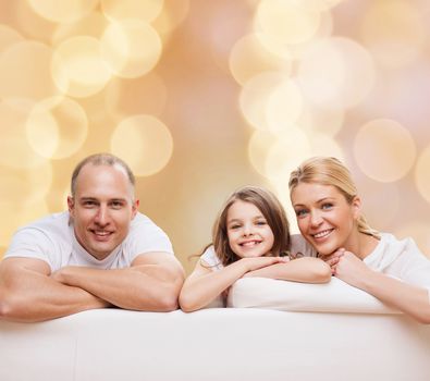 family, childhood, holidays and people - smiling mother, father and little girl over beige lights background